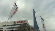 Gebäude der Firma Bosch sowie flatternde Fahnen mit dem Firmenlogo im Vordergrund. © Screenshot 