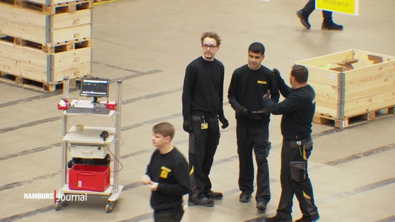 Arbeitende im Logistik-Bereich in einer großen Halle. © Screenshot 