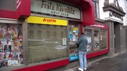 Ein Mann schließt die Tür zum "Kivelitz" Kiosk auf. © Screenshot 