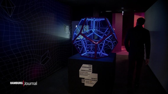 Ein leuchtendes geometrischen Ausstellungsstück in einem Museum. © Screenshot 