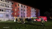 Feuerwehrmänner stehen vor einem Mehrfamilienhaus. © Screenshot 