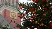 Hinter einem geschmücktem Weihnachtsbaum ist der Kieler rathausturm zu sehen. © Screenshot 