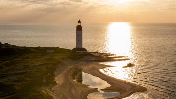 Ein Leuchtturm am Meer mit untergehender Sonne © Screenshot 