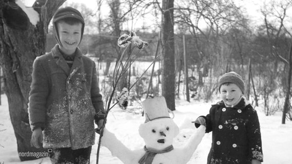 Ein altes schwarz-weiß-Foto zeigt zwei Kinder mit einem Schneemann. © Screenshot 