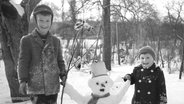 Ein altes schwarz-weiß-Foto zeigt zwei Kinder mit einem Schneemann. © Screenshot 