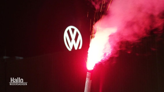 Ein rotes Bengalo-Feuerwerk, im Hintergrund das VW-Logo. © Screenshot 