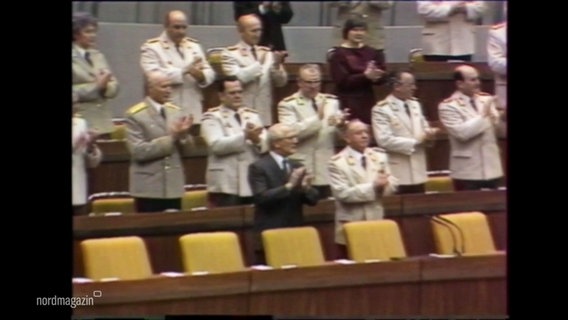 Bild aus der Volkskammer der ehemaligen DDR: Männer in Uniform applaudieren stehend. © Screenshot 