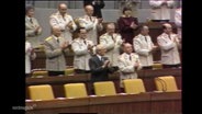 Bild aus der Volkskammer der ehemaligen DDR: Männer in Uniform applaudieren stehend. © Screenshot 