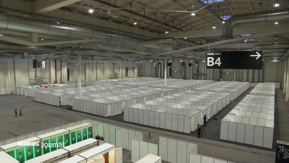 Blick in eine Halle der Hamburger Messehallen in der viele abgetrennte Aufenthaltsräume für Geflüchtete aufgebaut sind. © Screenshot 