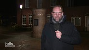 Reporter Sebastian Duden steht mit einem Mikro in der Hand im Dunkeln vor einem Haus. © Screenshot 