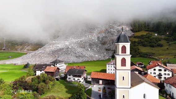 Ein Dorf in den Alpen, gefilmt von oben. © Screenshot 