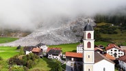 Ein Dorf in den Alpen, gefilmt von oben. © Screenshot 