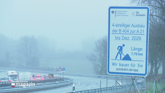 Auf einem Hinweisschild am Fahrbahnrand steht "4-streifiger Ausbau der B404 zur A21". © Screenshot 