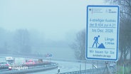 Auf einem Hinweisschild am Fahrbahnrand steht "4-streifiger Ausbau der B404 zur A21". © Screenshot 