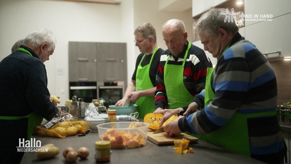 Vier Männer stehen in der Küche und kochen zusammen. © Screenshot 