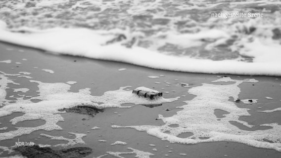 Ein Schwarz-Weiß-Foto eines an einem Strand angespülten, kleinen Päckchens. © Screenshot 