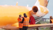 Ein mit orangener Farbe besprüter Privatjet. © Screenshot 