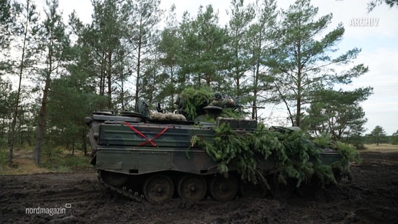 Ein mit Tannenzweigen getartner Panzer im Gelände. (Archivbild) © Screenshot 