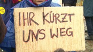 Ein Plakat mit der Aufschrift "Ihr kürzt uns weg". © Screenshot 