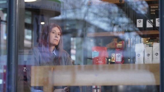 Eine Transfrau sitzt in einem  Café. © Screenshot 