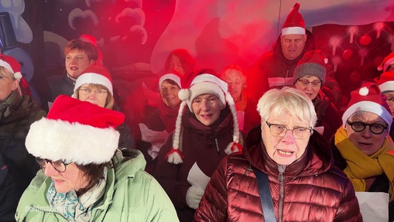 Ein Chor aus Weihnachtsmarktbesuchern singt Weihnachtslieder. © Screenshot 