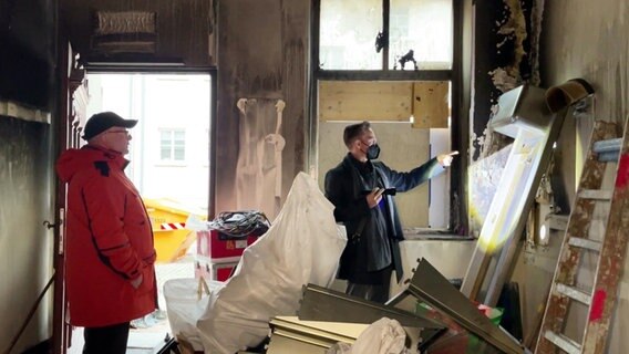 Stammgast Eckhard Brickenkamp und Inhaber Andreas Szabó sehen sich in der ausgebrannten Bar "B Sieben" in Rostock um. © Screenshot 