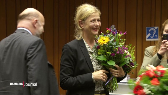 Bettina Schomburg lächelt und hält einen Blumenstrauß in der Hand. © Screenshot 