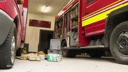 In dem Garagenraum einer Feuerwehrwache liegen Utensilien auf dem Boden verstreut. © Screenshot 