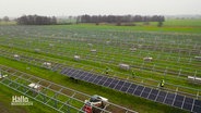 Blick aus der Vogelperspektive auf einen sich im Aufbau befindenden Solarpark auf einem Feld © Screenshot 