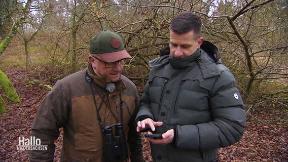 Zwei Jäger schauen zusammen auf ein Samrtphone im Wald. © Screenshot 