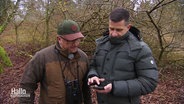 Zwei Jäger schauen zusammen auf ein Samrtphone im Wald. © Screenshot 