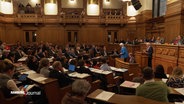 Sitzung der Hamburger Bürgerschaft im Rathaus. Der amtierende Oberbürgermeister Peter Tschtnscher (SPD) steht am Rednerpult. © Screenshot 