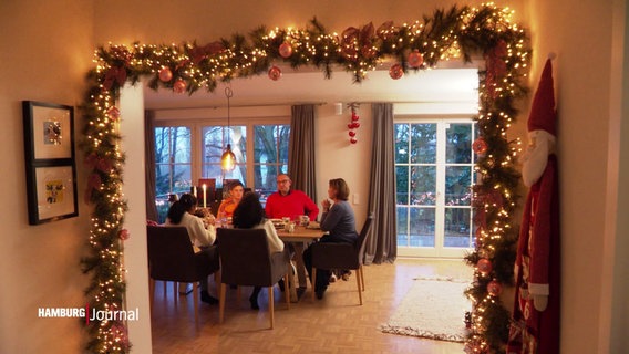 Menschen beim Essen in einem weihnachtlich geschmückten Zimmer. © Screenshot 