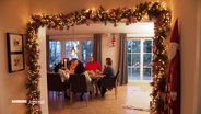 Menschen beim Essen in einem weihnachtlich geschmückten Zimmer. © Screenshot 