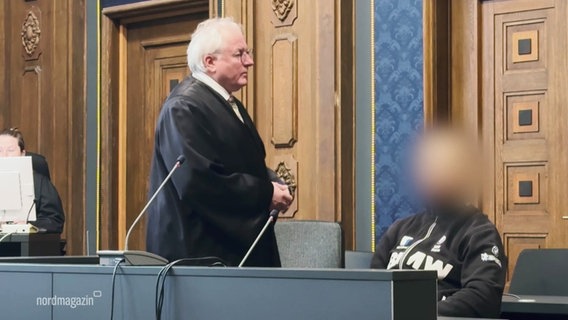 Richter und Angeklagter im Gerichtssaal, der Angeklagte wurde im Bild unkenntlich gemacht. © Screenshot 