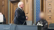 Richter und Angeklagter im Gerichtssaal, der Angeklagte wurde im Bild unkenntlich gemacht. © Screenshot 