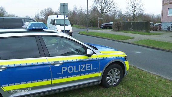 Ein parkendes Polizeiauto, im Hintergrund ein Einsatzfahrzeug mit Blaulicht. © Screenshot 