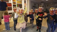 Kinder mit Masken aus Papier von der Kinderbuchfigur "Grüffelo". © Screenshot 