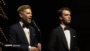 Sänger und Entertainer Tom Gaebel und ein weiterer Musiker in schwarzen Anzügen auf der Bühne. © Screenshot 