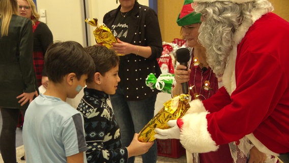 Ein Junge erhält ein Geschenk vom Weihnachtsmann. © Screenshot NDR Foto: Hans Tanz