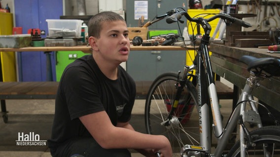 Ein Jugendlicher repariert in einer Werkstatt ein Fahrrad. © Screenshot 