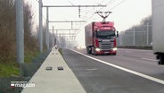 Ein Lastwagen fährt auf der Teststrecke des E-Highway mit einer Oberleitung auf der A1. © Screenshot 