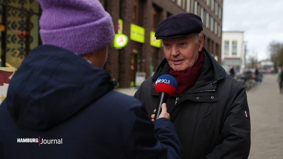 Ein Mann mit Schiebermütze wird interviewt © Screenshot 