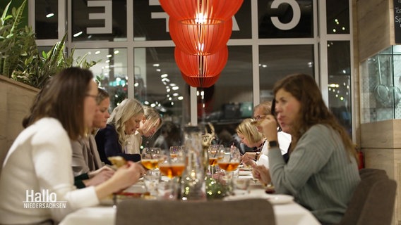 In einem Modekaufhaus sitzen mehrere Frauen an einer Tafel beim Essen. © Screenshot 