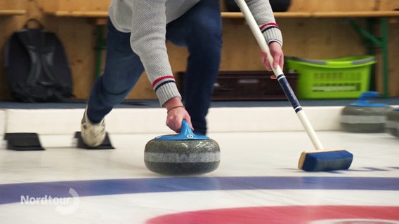 Ein Mann steht auf dem Eis und spielt Curling. © Screenshot 