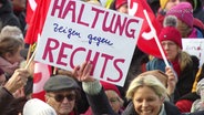 Eine Demonstrantin hält ein Schild bei einer Demo gegen Rechts hoch. © Screenshot 