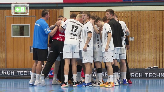 Handballspieler stehen bei einer Team-Besprechung in einem engen Kreis. © Screenshot 