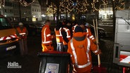 Mehrere Männer stehen mit Mülltonnen und Besen auf dem Rathausplatz. © Screenshot 