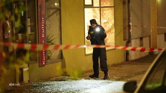 Eine Polizistin hinter einer Polizeiabsperrung vor einem Haus in Berlin. © Screenshot 