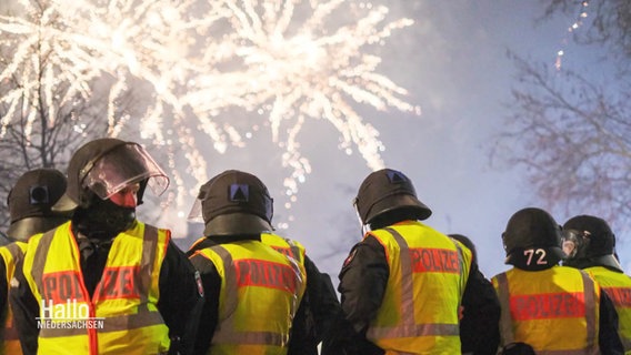 Mehrere Polizisten stehen beieinander, im Hintergrund explodiert Feuerwerk. © Screenshot 